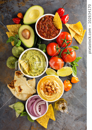 Homemade hummus, salsa and guacamole with corn chips 102634170