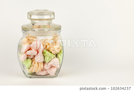 Homemade colored meringue in a glass jar on a white background. Homemade colored meringue in a glass jar on a white background. 102634237