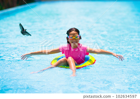 Child in swimming pool on toy ring. Kids swim. 102634597