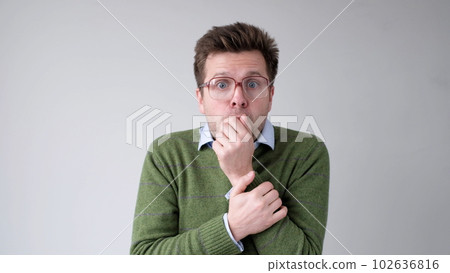 The European young man, in shock, covers his mouth with his hands, thinking, No, this is impossible. 102636816