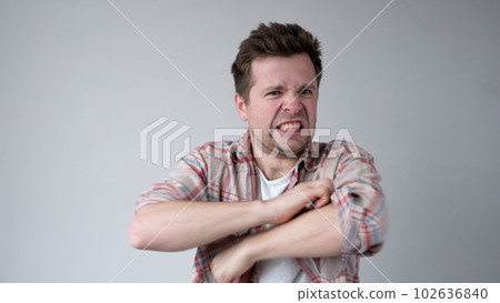 The European young man nervously scratches his hands. He has an allergy, and the itching bothers him The European young man nervously scratches his hands. He has an allergy, and the itching bothers him 102636840