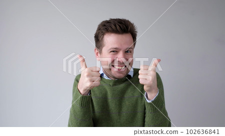 The European young man gives a thumbs up, approving the choice The European young man gives a thumbs up, approving the choice 102636841