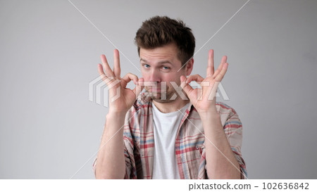 The European young man shows the okay gesture, saying everything is done excellently The European young man shows the okay gesture, saying everything is done excellently 102636842