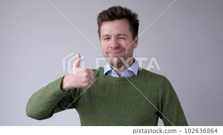 The European young man gives a thumbs up, approving the choice The European young man gives a thumbs up, approving the choice 102636864