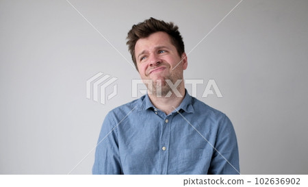 European young man is hesitating and unwilling to make decisions. He is upset about having to do unpleasant work. European young man is hesitating and unwilling to make decisions. He is upset about having to do unpleasant work. 102636902