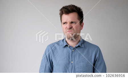 European young man is hesitating and unwilling to make decisions. He is upset about having to do unpleasant work. European young man is hesitating and unwilling to make decisions. He is upset about having to do unpleasant work. 102636916