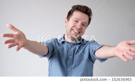 European young man is reaching out his hands forward to embrace the interlocutor, greeting him 102636965
