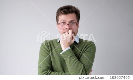 A European young man is nervous and biting his nails. A European young man is nervous and biting his nails. 102637405