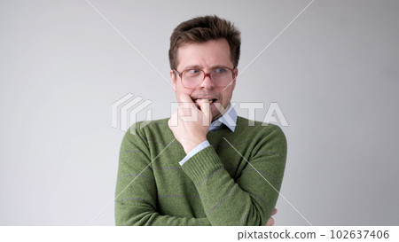 A European young man is nervous and biting his nails. A European young man is nervous and biting his nails. 102637406