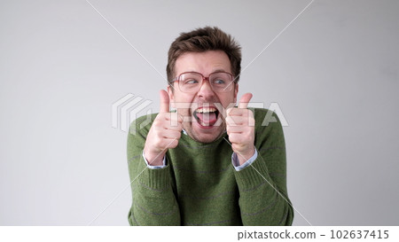 European young man shows a thumbs up. He is thrilled with the result 102637415