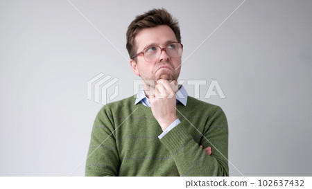 A European young man is rubbing his chin in doubt, thinking and making plans. 102637432