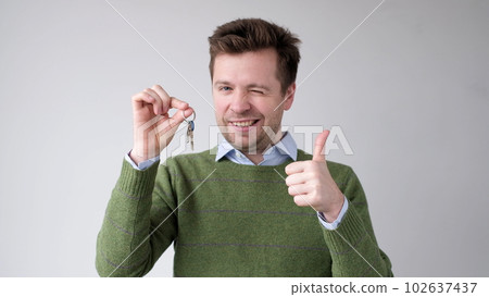 A European young man shows the keys to his new apartment. He is happy to have bought his own home 102637437