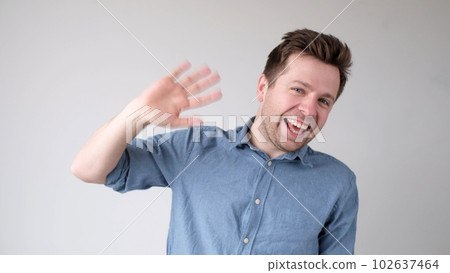 European young man waves his hand, greets his friends. European young man waves his hand, greets his friends. 102637464