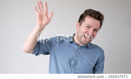 European young man waves his hand, greets his friends. 102637471