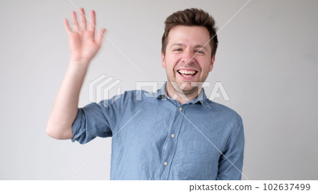 European young man waves his hand, greets his friends. European young man waves his hand, greets his friends. 102637499