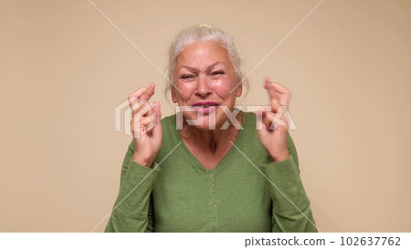 An elderly European woman crosses her fingers for good luck An elderly European woman crosses her fingers for good luck 102637762