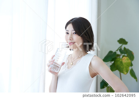 A woman drinking water in a room A woman drinking water in a room 102642095