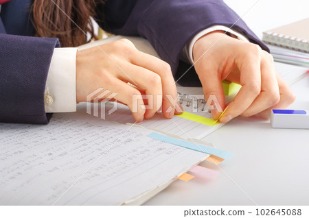 Female student pasting a sticky note on the text Female student pasting a sticky note on the text 102645088