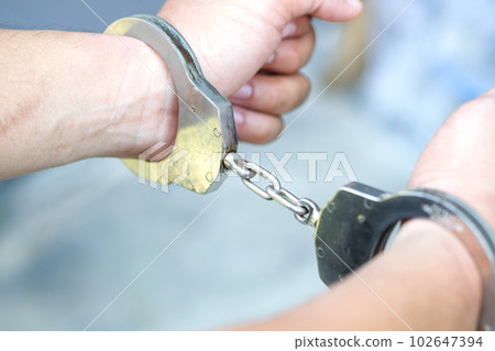 Men arrested and controlled by handcuffs on the wrist. The concept of offense and the law. 102647394