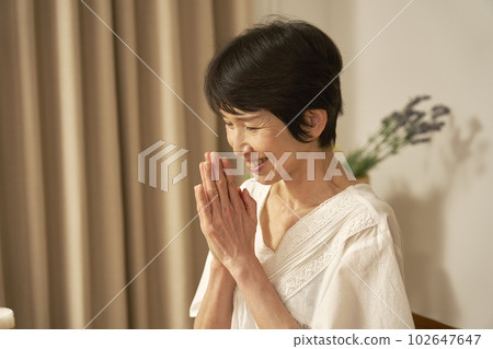 A middle-aged woman who puts her hands together at home A middle-aged woman who puts her hands together at home 102647647