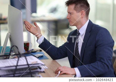 Disappointed employee looks at computer monitor at workplace 102648421