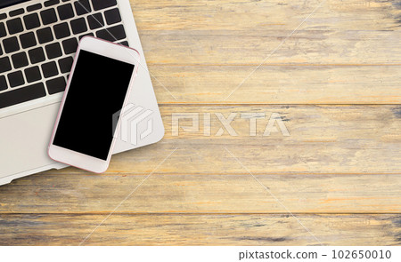 Smart phone and laptop computer on office desk or wood table. 102650010