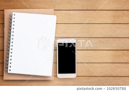 Empty blank paper notebook and smart phone on brown wooden table Empty blank paper notebook and smart phone on brown wooden table 102650788