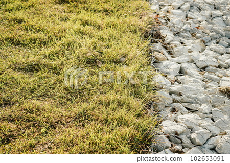 Granite stones behind a metal grate for strengthening the slope. Stones behind the wire. grey texture. construction. 102653091