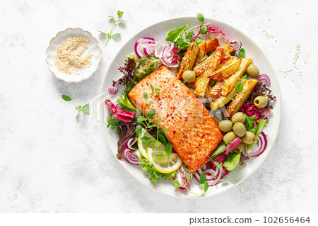 Salmon fillet grilled, fried potato and fresh vegetable green salad, top view 102656464