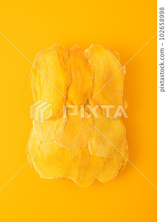 Large dried sweet mango slices on yellow background. 102658998