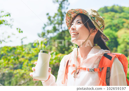 一位女士在攀登時用水瓶補充水分 102659197