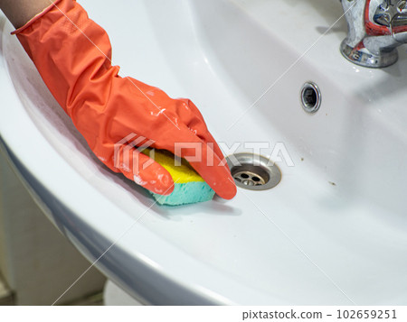 Person hand holding a mint sponge for cleaning bathroom sink and faucet Person hand holding a mint sponge for cleaning bathroom sink and faucet 102659251