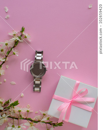 Womens wristwatch on pink background with cherry flowers and copy space 102659420