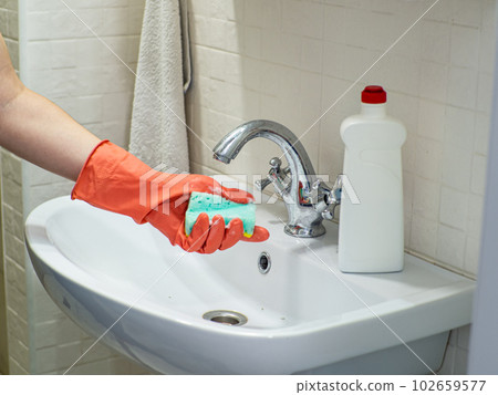 Person hand holding a mint sponge and washing it under water 102659577