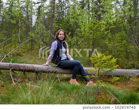 woman sitting on fallen tree in a green forest woman sitting on fallen tree in a green forest 102659748