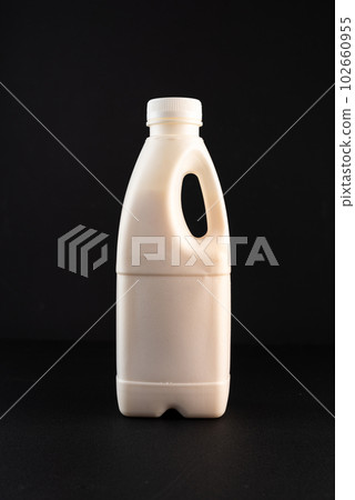 Bottle of milk with a handle. White bottle on a black background. Bottle of milk with a handle. White bottle on a black background. 102660955