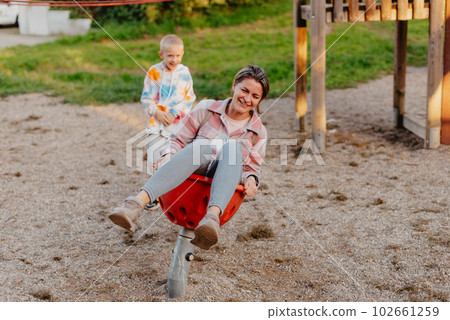 Mother and son having fun on a swing. Motherhood and childhood concept. Sunny summer day. Beautiful family is having fun outside. Parents with children riding on a swing. Mom is playing with her Mother and son having fun on a swing. Motherhood and childhood concept. Sunny summer day. Beautiful family is having fun outside. Parents with children riding on a swing. Mom is playing with her 102661259