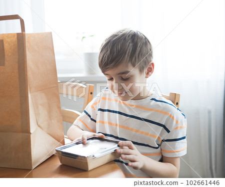 The boy looks into a craft package with food delivery or a parcel. 102661446