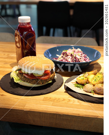 Lunch on the counter in the shopping center, business center. Burger, fries, cole salad and drink. 102661481
