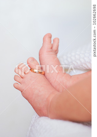 Wedding ring on the thumb of small children's legs on white background Wedding ring on the thumb of small children's legs on white background 102662698