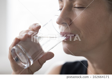 Happy serene attractive mature lady drinking mineral fresh pure water 102664171