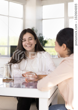 Two cheerful multiethnic girls laughing sit at table in cafe Two cheerful multiethnic girls laughing sit at table in cafe 102664893