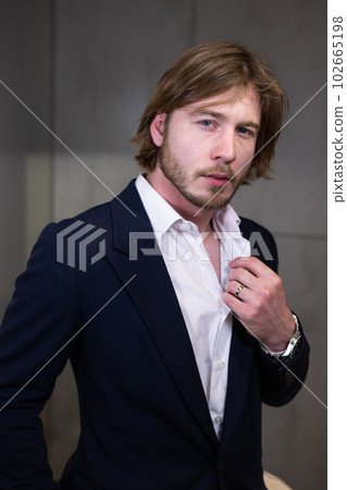 Portrait of a man in a jewelry store. Guy wearing a wedding ring and an expensive watch, poses for a business portrait. The stylish and handsome male looks into the camera. Portrait of a man in a jewelry store. Guy wearing a wedding ring and an expensive watch, poses for a business portrait. The stylish and handsome male looks into the camera. 102665198