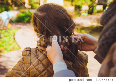 The mother braids her daughter's hair 102665323