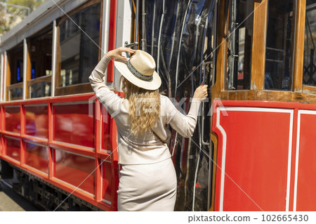 Beautiful young girl tourist in a hat poses in front of tram at popular Istiklal street in Beyoglu, Istanbul, Turkey Beautiful young girl tourist in a hat poses in front of tram at popular Istiklal street in Beyoglu, Istanbul, Turkey 102665430