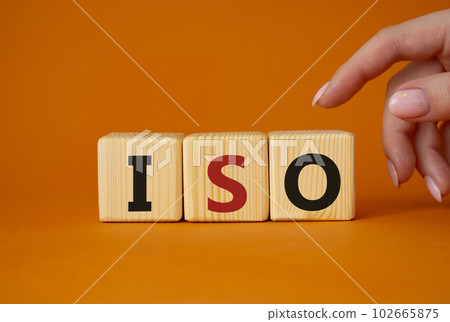 ISO standards quality control symbol. Concept word ISO on wooden cubes. Businessman hand. Beautiful orange background. Business and ISO concept. Copy space. ISO standards quality control symbol. Concept word ISO on wooden cubes. Businessman hand. Beautiful orange background. Business and ISO concept. Copy space. 102665875