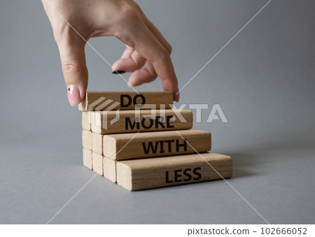 Do more with less symbol. Concept words Do more with less on wooden blocks. Beautiful grey background. Businessman hand. Business and Do more with less concept. Copy space. Do more with less symbol. Concept words Do more with less on wooden blocks. Beautiful grey background. Businessman hand. Business and Do more with less concept. Copy space. 102666052