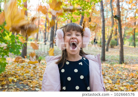 Outdoor portrait of happy little girl in autumn park with falling leaves 102666576