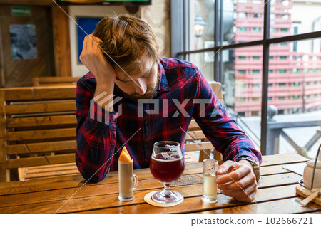 A drunk man at a bar, sitting alone at a table. Fight against alcohol addiction, crisis 102666721