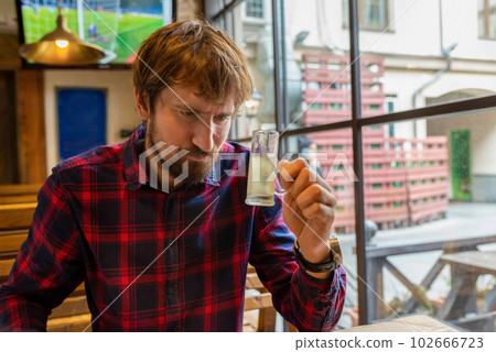 A man sits alone at a table in a bar and drinks strong alcohol. Alcoholism, alcohol addiction A man sits alone at a table in a bar and drinks strong alcohol. Alcoholism, alcohol addiction 102666723